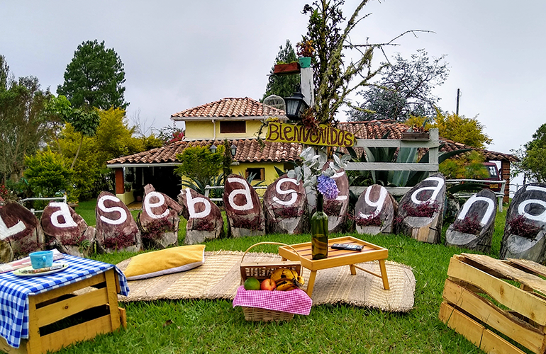 Mensaje de bienvenida para los turistas frente a casa tradicional antioqueña