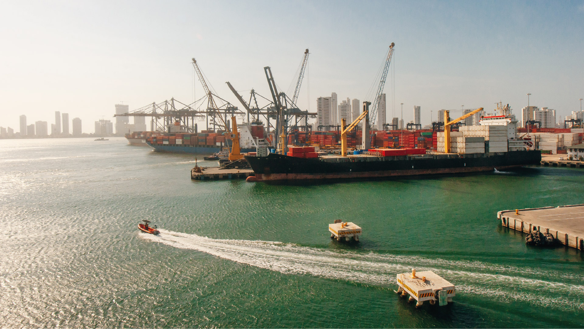 Puerto marítimo con grúas, barcos de carga y contenedores.