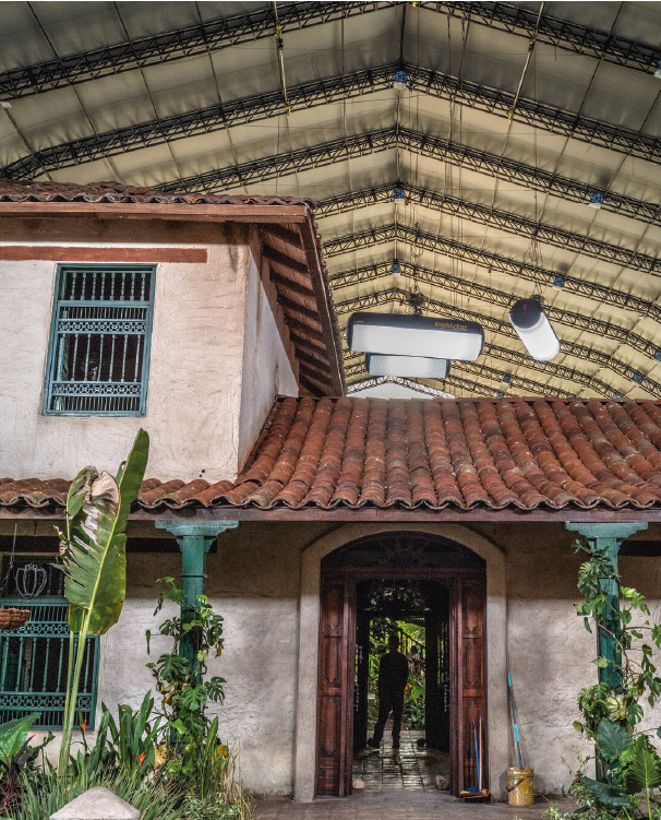 Maison coloniale avec un toit de tuiles et une personne à l’entrée.