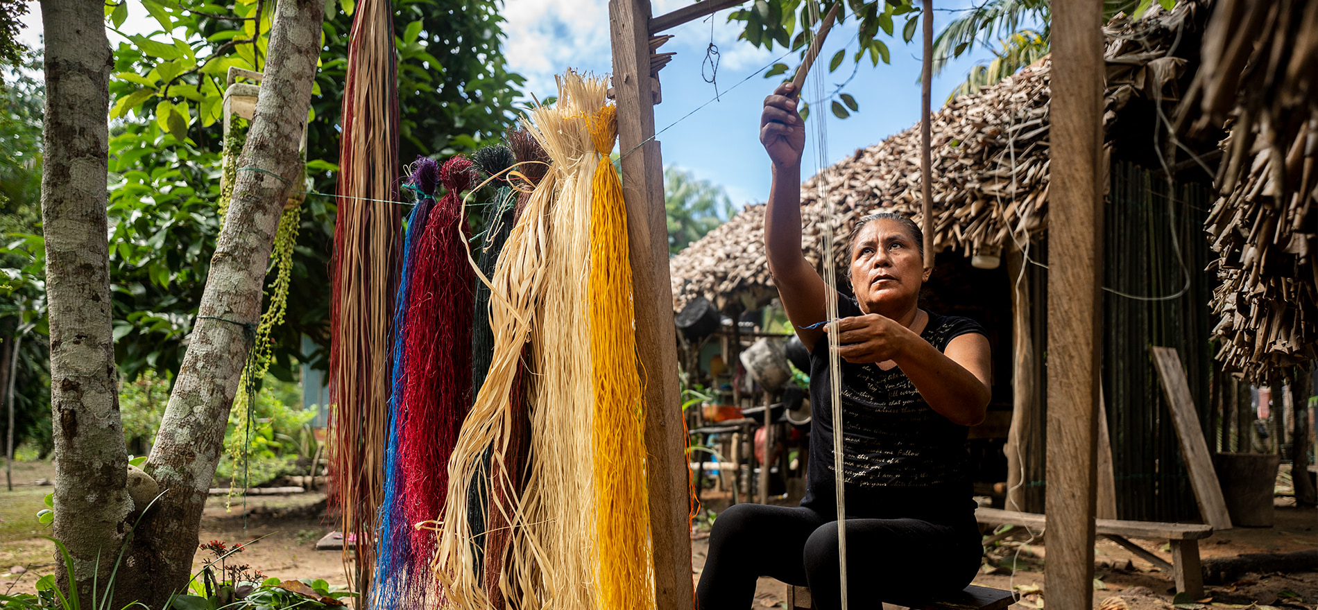 mujer campesina en rancheria tejiendo y haciendo artesanias de colombia.