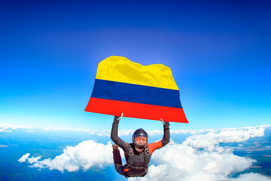 Paracaidista en caída libre sosteniendo la bandera de Colombia