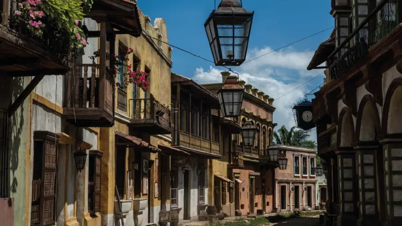 Colonial street with colorful houses and hanging lanterns.