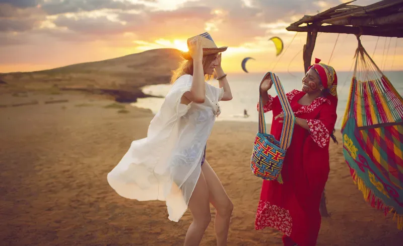 A Wayúu indigenous woman gives a brightly colored native bag to a foreign tourist. La Guajira is part of the García Márquez route in the Colombian Caribbean