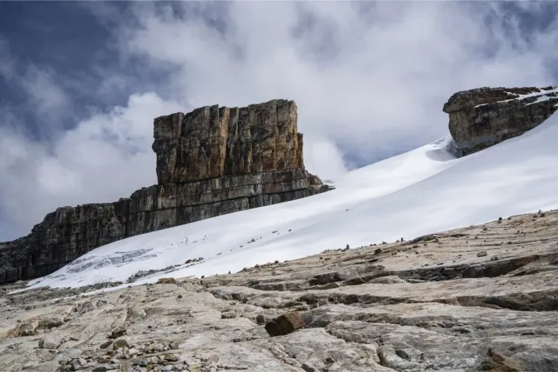 Tabular and rugged rock formation next to a snow-covered slope in the Sierra Nevada del Cocuy.