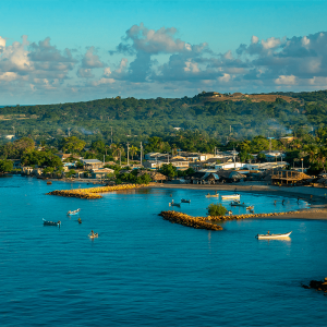 Cielo azul con nubes, vegetación verde, mar azul con pequeñas embarcaciones en la Isla de Tierra Bomba