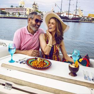 Una pareja sonriente disfruta de un delicioso almuerzo a orillas del mar en Cartagena.
