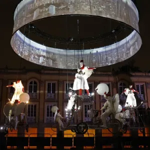 Espectáculo aéreo nocturno con artistas suspendidos y proyección circular