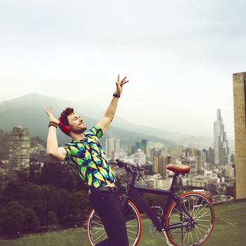Un joven con una camiseta colorida escucha música en un rooftop de Bogotá.