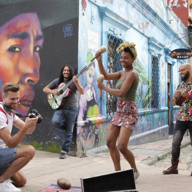 A tourist couple takes a picture of a Colombian musical group while enjoying the rhythm of the music.